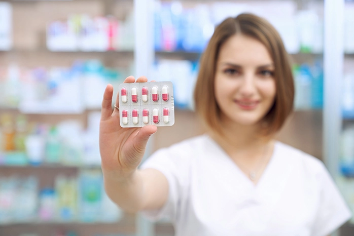 woman pharmacist holding birth control packet of pills