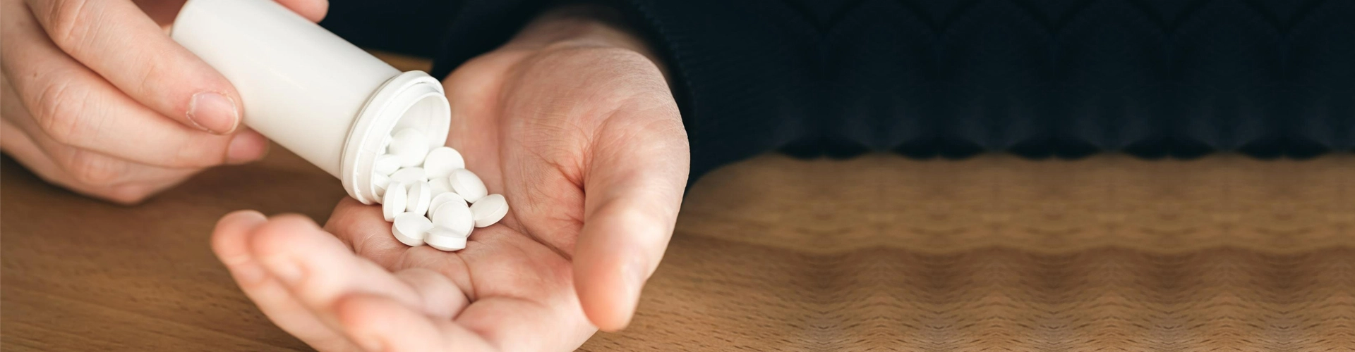 man dumping white pills into his hand