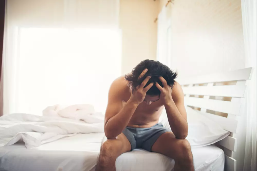 worried man sitting on a bed