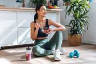 woman eating healthy food with weights nearby
